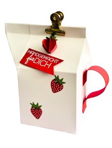 Geschenkverpackung mit einer Leckereibox und Erdbeeren